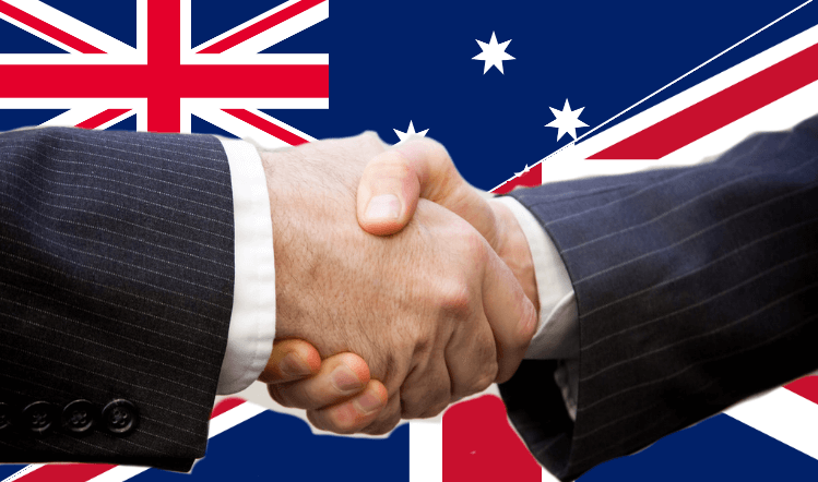 shaking hands in front of australia and UK flags
